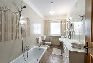 Appartamento a Canazei. spaziosa stanza da bagno che dispone di lavandino, bidet, WC, vasca, asciugacapelli e finestra