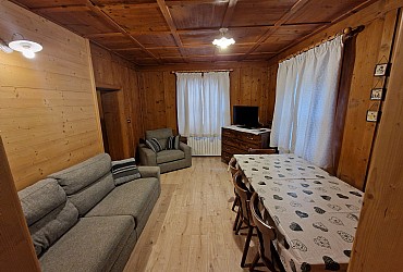Appartamento a Soraga di Fassa. soggiorno: tavolo con 8 comodi posti a sedere, divano 3 posti, poltrona, due finestre, tv, wi-fi. Il soggiorno è la tipica stube in legno restaurata ed ammodernata per restituire le calde ed avvolgenti atmosfere di montagna e del mondo ladino.