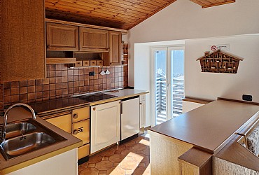 Appartamento a Soraga di Fassa. Il salotto con l'angolo cottura. Cucina in vetroceramica a 4 fuochi, frigorifero, lavello a 2 vasche, lavastoviglie, bollitore e, a richiesta, forno a microonde. In salotto, come in tutte le stanze, si può usare la nostra wi-fi gratuita, previa acquisizione della password.