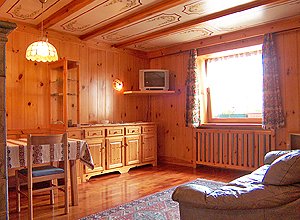 Appartamento a Moena. Al terzo piano si trova un appartamento arredato in stile ladino: pareti perlinate cirmolo, soffitto in cassettoni di legno decorati a mano e arredi di fattura artigianale locale.