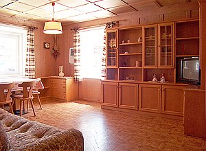 Appartamento a San Giovanni di Fassa - Pozza. L’ampio salotto ha le caratteristiche di una tipica “stua” ladina, interamente rivestito in legno.