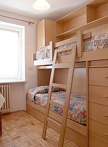 Appartamento a Campitello di Fassa. Camera con letto a castello con cassetti ed armadio.