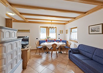 Wohnung - Campitello di Fassa. The Marmolada apartment, 70 MQ, has a living-dining room with a sofa along one wall and a table and chairs for dining. There is also a TV to watch while relaxing after skiing, and a traditional Tyrolean radiant room heater.