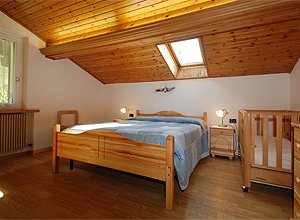 Appartamento a Moena. AMPIA CAMERA MATRIMONIALE CON FINESTRA VELUX E FINESTRA A MURO CHE DA VERSO IL PRATO E IL BOSCO DI MOENA