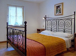 Appartamento a Penia di Canazei. Nella camera da letto matrimoniale è possibile aggiungere all'occorrenza una culla. La camera offre anch'essa una veduta panoramica.