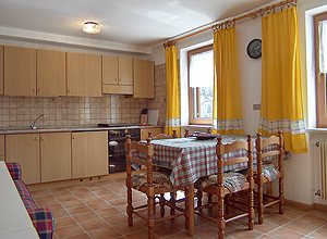 Appartamento a San Giovanni di Fassa - Pozza. CUCINA - SOGGIORNO CON PIANO COTTURA, DIVANO E TELEVISORE A COLORI.  VERANDA ESTERNA.