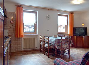 Appartamento a San Giovanni di Fassa - Pozza. CUCINA - SOGGIORNO CON PIANO COTTURA, DIVANO E TELEVISORE A COLORI. VERANDA ESTERNA.