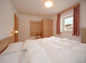 La Villetta - Ein Doppelschlafzimmer mit schoener Aussicht ueber die Sassolungo Spitze.