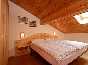 Appartamento a Canazei. Camera in stile montano dipinta a mano, biancheria da letto fornita.