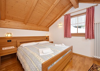 Appartamento a San Giovanni di Fassa - Vigo . La zona notte, disposta al secondo piano, è raggiungibile attraverso una comoda scala in legno, costruita in stile tradizionale, in linea con i tratti peculiari della zona.
La zona é costituita da due camere da letto:
- una camera matrimoniale, con caldo piumino, spaziosi armadi e piccola scrivania.
- Una camera doppia, con letti singoli, due piumoni ed ampi armadi. La stanza è dotata di balcone con splendida vista sul paese e sulle montagne del Cima Undici, Cima Dodici e Roda di Vael.
Il secondo piano è inoltre dotato di un altro bagno con doccia, phon, lavandino, specchio e sanitari. Il riscaldamento centralizzato è presente in tutta la struttura.