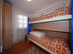 Appartamento a Moena. camera con due letti singoli. Il letto sopra è accessibile comodamente attraverso due comodi cassetti che fungono da scalini.