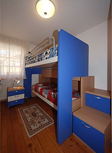 Appartamento a Moena. camera con due letti singoli. Il letto sopra è accessibile comodamente attraverso due cassetti che fungono da scalini.