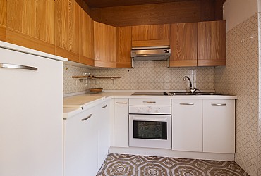 Appartamento a Moena. Cucinotto fornito di angolo cottura con piastra vetro-ceramica, forno, frigorifero e lavastoviglie.
