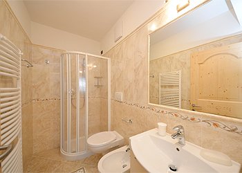 Appartamento a Moena. Un bagno arredato sui toni del nocciola ha la doccia, un caldo termo- bagno completa l'arredamento.