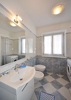 Appartamento a Moena. Il secondo bagno è arredato sui toni dell'azzurro, ha doccia, lavatrice e un caldo termo bagno scaldasalviette.