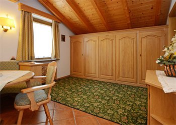 Appartamento a Moena. Seconda camera con TV LCD, accesso a un secondo bagno, piccolo balcone, tavolo, panca e sedie, poltrone, doppio letto ribaltabile.