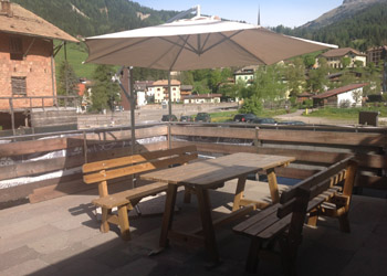 Appartamento a Moena. Ampia terrazza soleggiata privata dotata di tavolo ed ombrellone  per pranzare all'aperto o come solarium . L'appartamento e' dotato di parcheggio privato a 3 mt a dx  dalla scala nella foto dal basso.