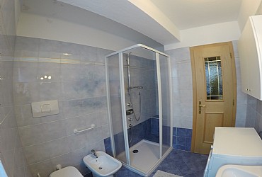Apartment in Canazei. There are two bathrooms with windows. The big one holds utilities, wash-basin with mirror, bathtub, washing machine and phon.