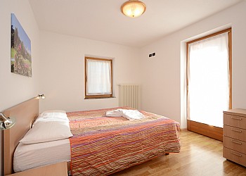Appartamento a San Giovanni di Fassa - Vigo. Camera con letto matrimoniale con possibilità di aggiungere un letto e dalla quale si può accedere all' ampio balcone ben esposto al sole, dal quale si può godere di un bellissimo panorama su Cima Dodici e si può passare un pò di tempo in tutto relax.