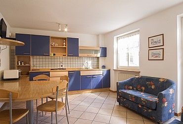 Wohnung - Moena. Dreiraumwohnung mit 4 Betten.
Wohnzimmer mit Balkon; Kocharea: Gasherd, Kuehlschrank.