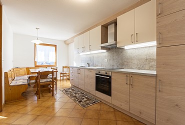 Appartamento a Moena. Cucina abitabile pulitissma, in legno di pino, fornita di frigorifero,frizer, piano ad induzione con forno ad elettrico e asse da stiro con ferro.
