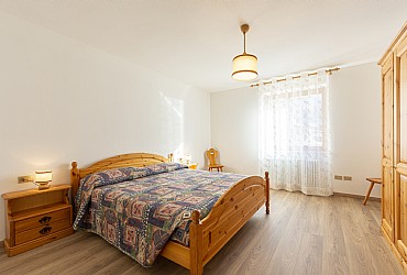 Appartamento a Moena. Ampia stanza matrimoniale, in legno di pino, con la possibilità di aggiungere comodamente un terzo letto o lettino con spondine.
