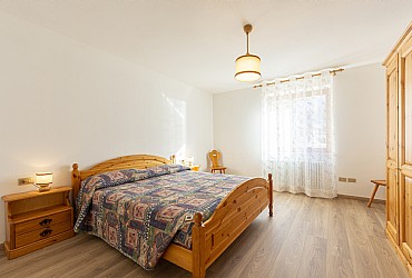 Appartamento a Moena. Ampia stanza matrimoniale, in legno di pino, con la possibilità di aggiungere comodamente un terzo letto o lettino con spondine.