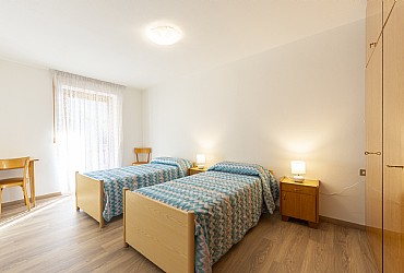 Appartamento a Moena. Ampia stanza a due letti o matrimoniale, con la possibilità di aggiungere un terzo letto con accesso al balcone.