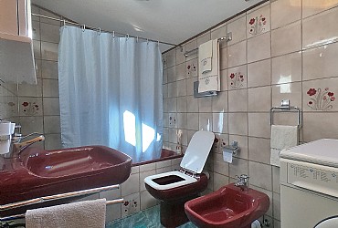 Apartment in Canazei. Bathroom with window, bathtub and wash machine.