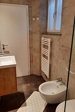 Appartamento a Soraga di Fassa. Questo servizio è completo di doccia (con piatto a sfioro pavimento), lavandino, WC e bidet. Finestrato con accesso dalla seconda camera.
