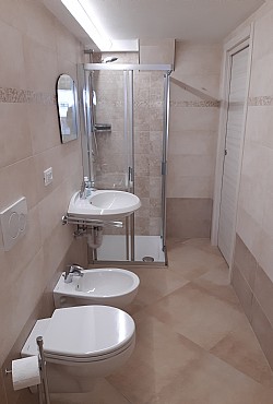 Appartamento a Canazei. Luminoso bagno finestrato completo di box doccia, wc, bidet e phon asciugacapelli.