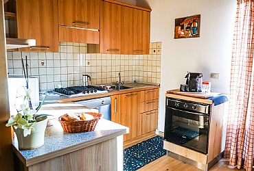 Appartamento a Campitello di Fassa. Angolo cottura con gas 4 fuochi, forno, frigorifero (a disposizione anche ferro da stiro) ed accesso al balcone con sedia sdraio ed ombrellone.