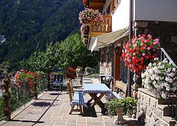 Appartamento a Predazzo. L'appartamento ha un tavolo esterno e un prendi sole.